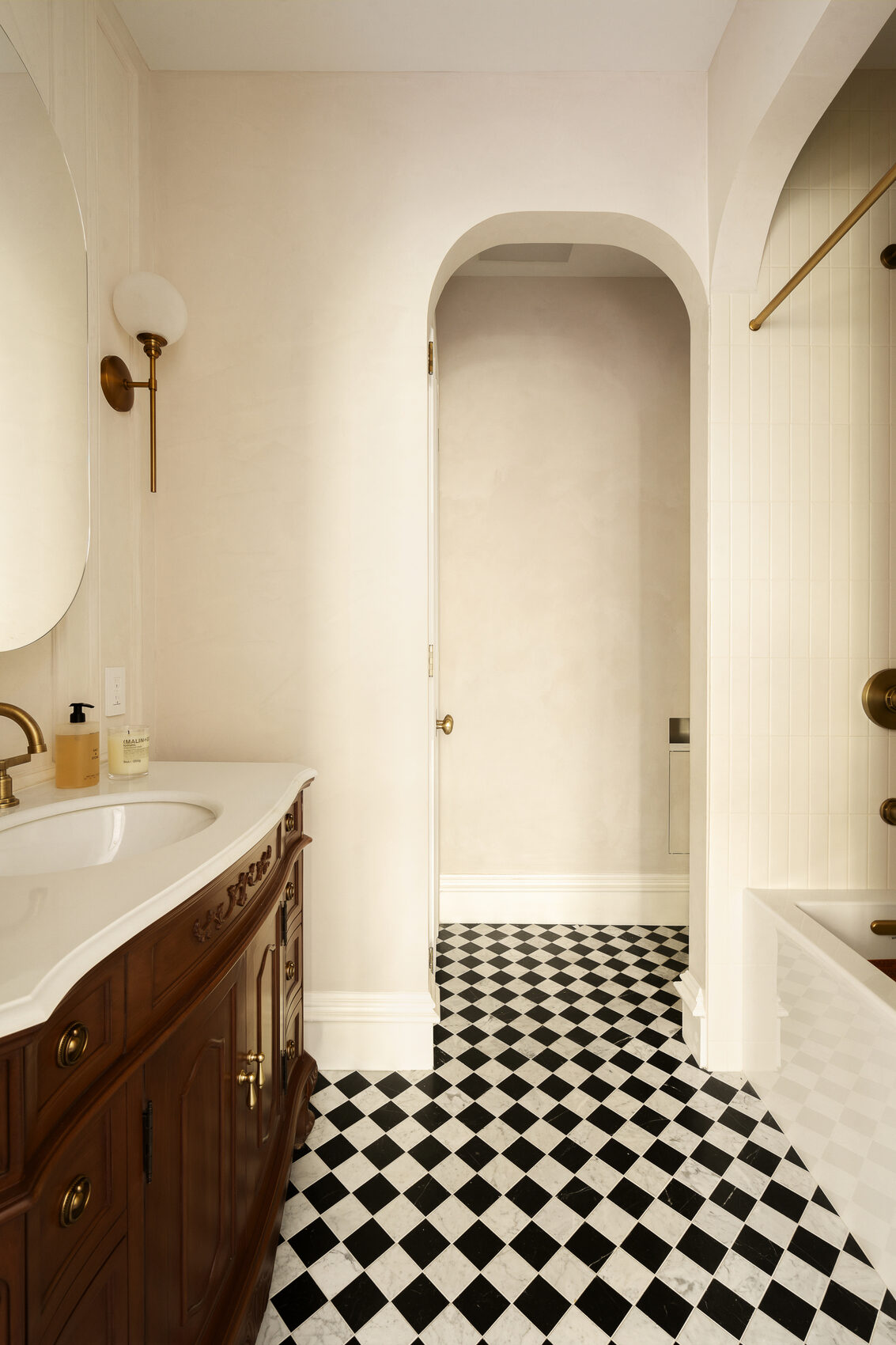 The renovated primary bath at № 428 — checkered marble floor and aged brass fixtures
