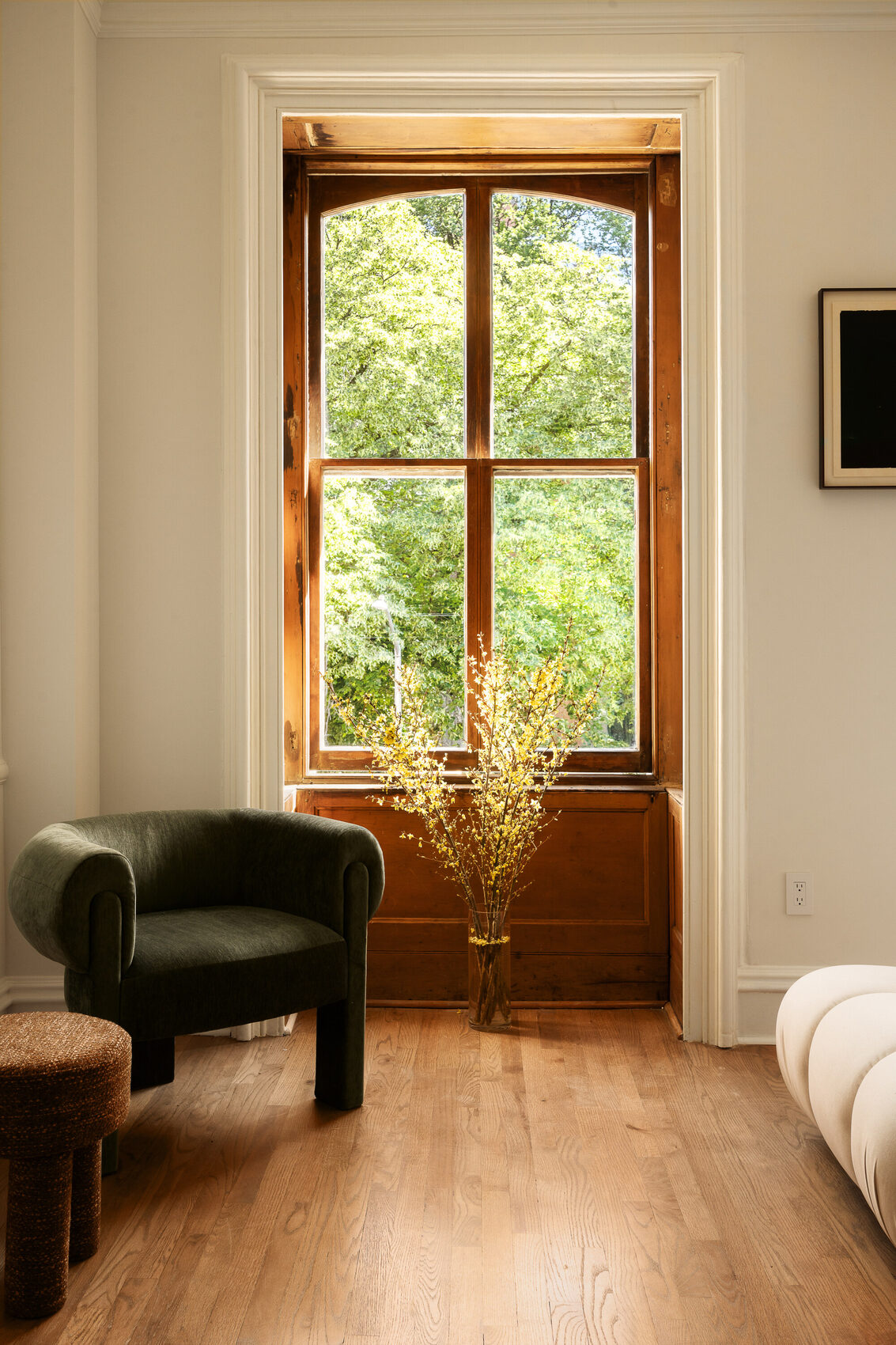 A tall window of 428 West 20th Street, framing the trees of the seminary block